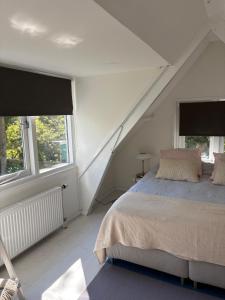 a white bedroom with a bed and two windows at Blossom in Bergen
