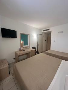 a bedroom with two beds and a desk and a television at Hotel Bulla Regia in Fontane Bianche
