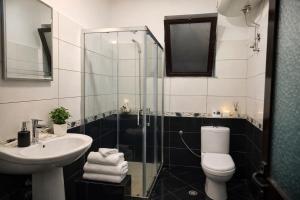 a bathroom with a sink and a toilet and a shower at Spacious Triple Room with Balcony in Kamëz