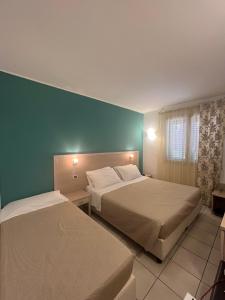 a bedroom with two beds and a green wall at Hotel Bulla Regia in Fontane Bianche +40 photos