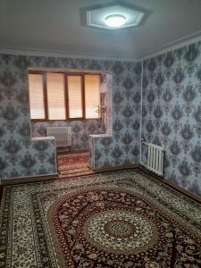 an empty room with a large rug and a window at UYUT INN apartment in Samarkand +1 photo