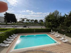 a swimming pool with lounge chairs and a road at Hotel Bulla Regia in Fontane Bianche