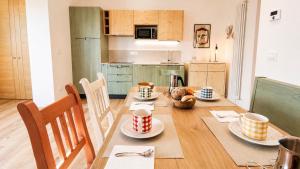 a kitchen with a table with cups and plates on it at Verde Betulla, Free Park and Ski room in Camporosso in Valcanale