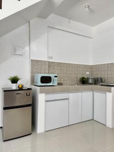 a kitchen with white cabinets and a microwave at Sebastians CRIB D in Dasmariñas