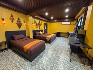 a room with two beds and a desk and a television at Phoenix Room in Ban Tha Samet (1)