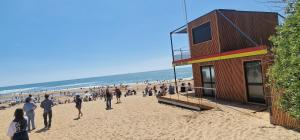 a crowd of people on a beach with a building at Maisonnette duplex 4 pers proche mer et golf in Talmont