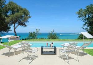 a swimming pool with two chairs and a table with a table at Villa Krizia - Ancona, meravigliosa villa con piscina vista mare in Ancona