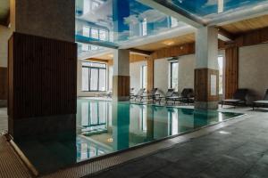 a swimming pool in a building with chairs at Albert Mountain Retreat & SPA in Lepşa