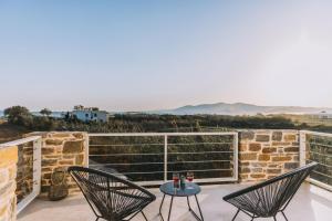 a patio with two chairs and a table on a balcony at Naxos Cube Villa Panoramic Views Maisonette with Sea View 2 min walk to Plaka Beach in Plaka