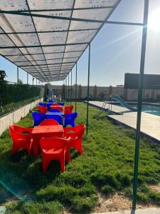 a group of red and blue tables and chairs under a canopy at Villa Layan الريف الاوروبي in Madīnat as Sādāt