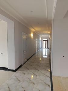 an empty hallway with white walls and a marble floor at Ibrohim Xoja Hotel in Khiva