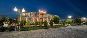 two people sitting on a bench in front of a hotel at Ibrohim Xoja Hotel in Khiva