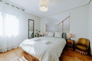 a bedroom with a large white bed and a chair at Casa Raíces de PO in Lapoblación