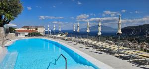 a swimming pool with chairs and a view of the ocean at Hotel Cristina in Sorrento