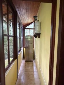 a hallway with a refrigerator in a room with windows at Sitio vale das araucarias in Araras Petropolis