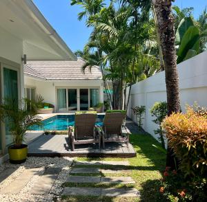 a backyard with two chairs and a swimming pool at Baan Tai Tara 4, Private Pool Villa by Ban Tai Beach in Ban Tai