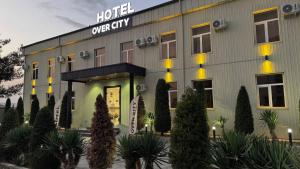 a hotel with a sign on the front of it at Over City Hostel in Margilan