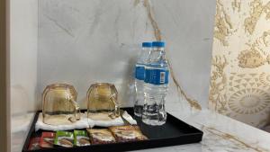 a bottle of water and two glasses on a tray at Over City Hostel in Margilan