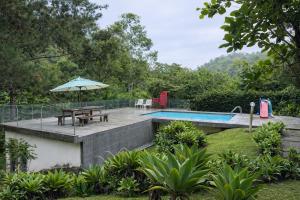 a swimming pool with a picnic table and an umbrella at Sitio vale das araucarias in Araras Petropolis