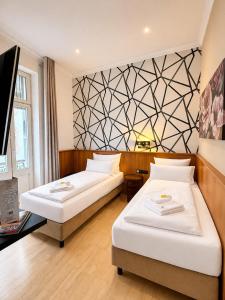 a hotel room with two beds and a tv at Hotel Porta Nigra VICTUS in Trier
