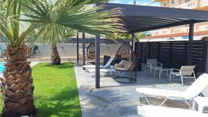 a patio with a black canopy and chairs and palm trees at Luana Monte Apartments in Amoudara Herakliou