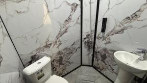 a bathroom with a toilet and a sink at Over City Hostel in Margilan