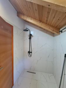 a shower in a bathroom with white marble walls at Guest House Korabi in Ceren