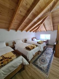four beds in a room with wooden ceilings and a rug at Guest House Korabi in Ceren