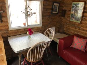 a dining room with a table and chairs and a red couch at East cross forest log cabin in Burketon Station