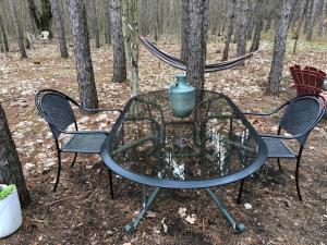 a glass table with two chairs and a vase on top at East cross forest log cabin in Burketon Station +10 photos