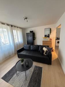 a living room with a black couch and a table at Centre ville - Le Creusot in Le Creusot