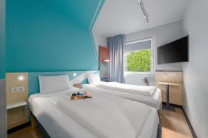 two white beds in a room with a blue wall at Ibis Budget Leipzig City in Leipzig