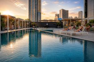 a hotel swimming pool with two people laying in lounge chairs at Millennium Central Downtown - Dubai in Dubai