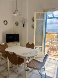 a dining room with a table and chairs and a television at Sylvia Studios in Agia Marina Aegina