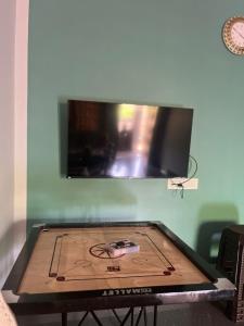 a ping pong table with a tv on the wall at Grass root by shelters in Vayittiri