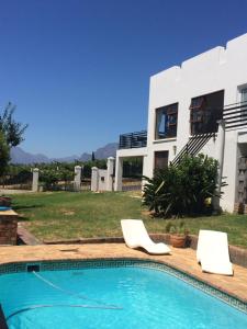 a house with a swimming pool and two white chairs at Paarl Mountain Lodge in Paarl