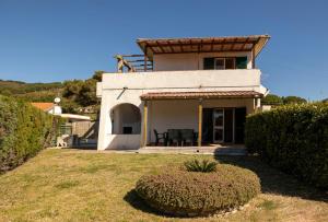 a white house with a table and chairs in a yard at Lacona Mare - HelloElba in Lacona