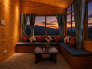a room with a couch with a table and a window at APine Cottages - Two Bedroom, One Luxury Getaway in Nārkanda