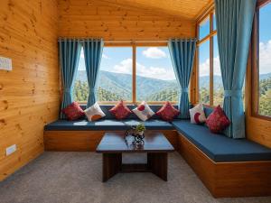 a room with a blue couch with pillows and a table at APine Cottages - Two Bedroom, One Luxury Getaway in Nārkanda