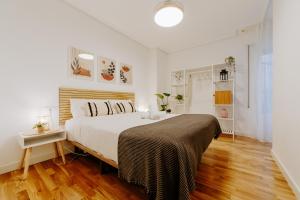 a white bedroom with a large bed and wooden floors at Alojamiento en pleno centro con WIFI y Aire Acondicionado in Logroño