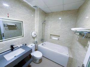 a bathroom with a white tub and a toilet and a sink at Hoom Villa Thành Nội - Villa 3 phòng ngủ in Thôn An Hòa