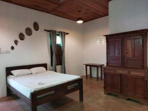 a bedroom with a bed and a wooden cabinet at Karisal Resort & Park in Jaffna