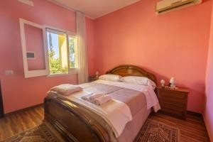 a bedroom with a bed with pink walls and a window at Casa Vacanza Capozzoli in Albanella