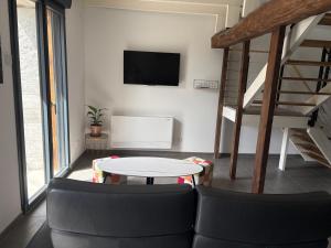 a living room with a table and a tv at La Fraternelle in Ceyzérieu