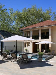 a patio with chairs and umbrellas in front of a house at Mirage Apartments & Pool - Balatonboglar in Balatonboglár