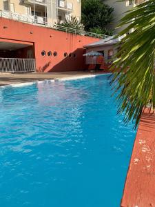 a swimming pool with blue water in front of a building at Studio SUCRIER TARTANE in La Trinité