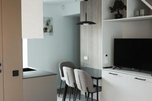 a dining room with a table and chairs and a television at Jaukus loftas Šventoji in Šventoji