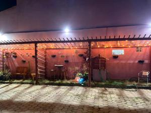 a patio with a red wall with lights on it at Pequena Sereia Guriri in São Mateus