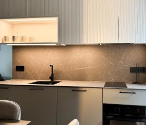 a kitchen with white cabinets and a sink at Jaukus loftas Šventoji in Šventoji +13 photos