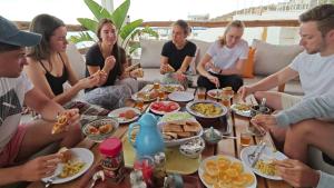 a group of people sitting around a table eating food at BigBlue Surf Experience Hostel in Taghazout